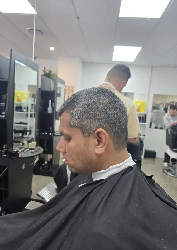 Trainee barbers standing near a vintage barber chair on the training floor