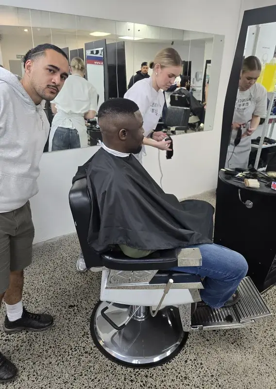 Purple-walled barbering room with a row of reclining chairs and a street-facing entrance