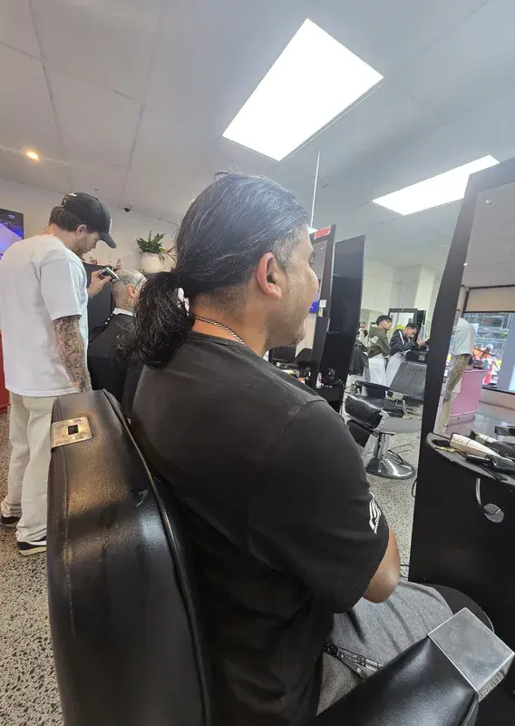 Barber trimming a client's neckline while two colleagues look on