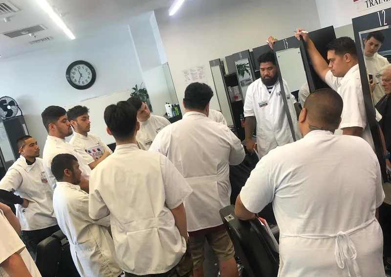 Trainee barbers in white coats during a group training session on the shop floor